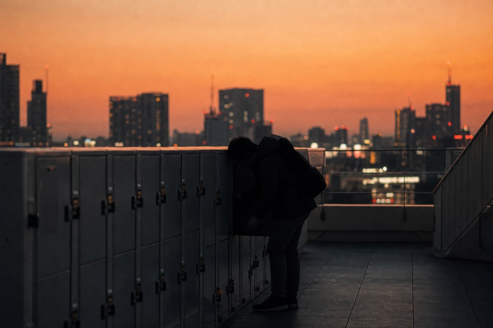 Row of small coin-operated lockers on an observation floor with a visitor stowing a backpack before heading up to a rooftop